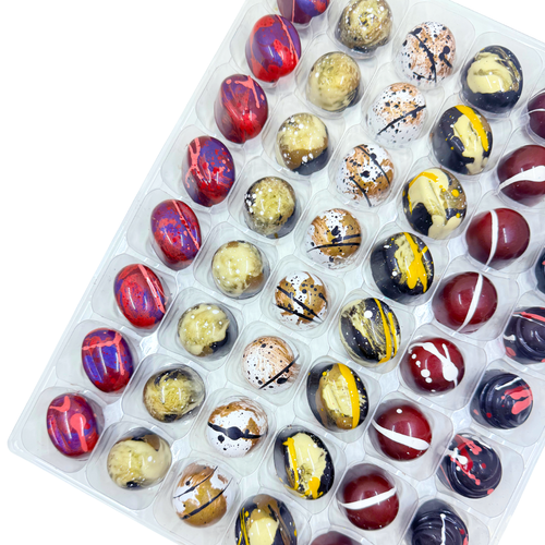 Assorted chocolate bonbons in a clear plastic container on a white background