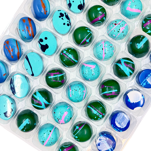 Assorted chocolate bonbons in a clear plastic container on a white background