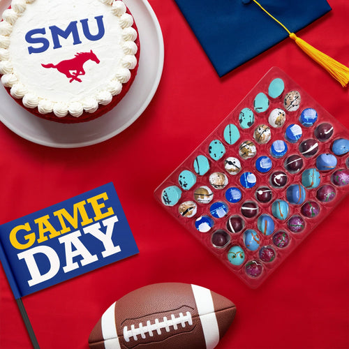 An assortment of chocolate bonbons with decorative football and graduation-themed items on a red background, celebrating SMU graduation and game day.