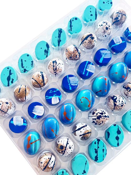Assorted chocolate bonbons in a clear plastic container on a white background