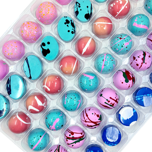 Assorted chocolate bonbons in a clear plastic container on a white background