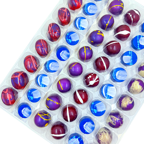 Assorted chocolate bonbons in a clear plastic container on a white background
