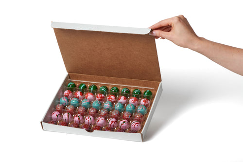 Hand opening a box of colorful Christmas bonbons on a white background
