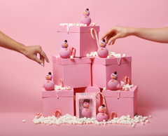 Pink gift boxes with pink mini snowmen and candy canes and marchmellows on a pink background