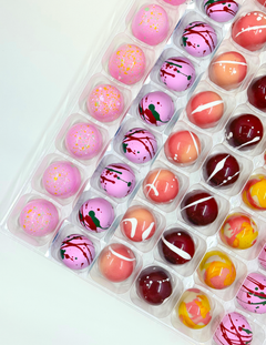 Assorted chocolate bonbons in a clear plastic container on a white background