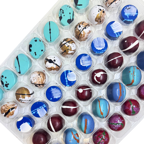 Clear tray of cool toned colored bonbons