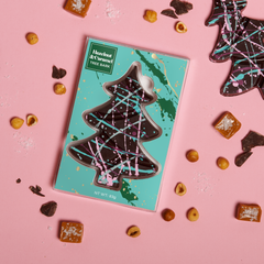 Chocolate tree-shaped chocolate candy bar on a pink background with a teal packaging box.
