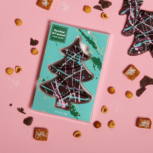 Chocolate tree-shaped chocolate candy bar on a pink background with a teal packaging box.