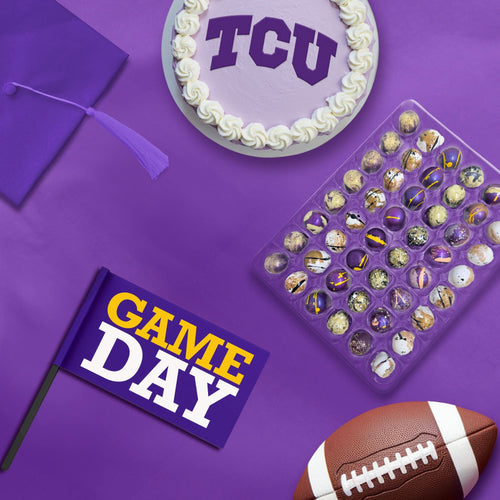 A collection of TCU-themed chocolate bonbons displayed on a purple surface, along with a 'TCU' cake, a 'GAME DAY' flag, and a football, indicating a graduation or game day celebration.