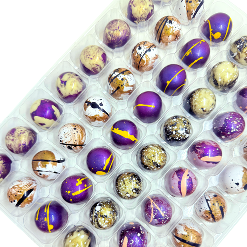 Assorted chocolate bonbons in a clear plastic container on a white background