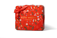 Red chocolate tin with festive design and 'kate weiser' branding on a white background