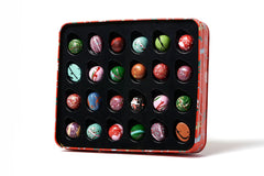 Assorted colorful chocolates in a decorative tin on a white background