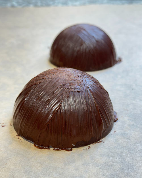 Two chocolate truffles on a baking sheet