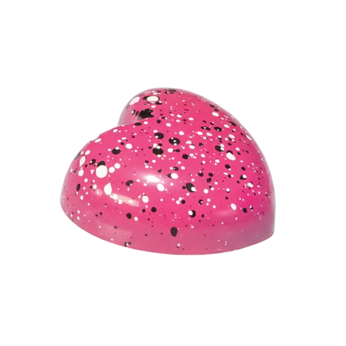 Pink heart-shaped bonbon with black and white speckles on a white background