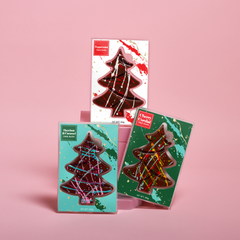Three chocolate tree-shaped bars in different packaging on a pink background