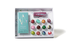 Box of colorful chocolate bonbons with a teal Kate Weiser chocolate bar and a purple candy bar in a white box on a white background